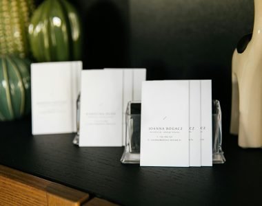 Set of simple visit cards on shelf composed with various stylish vases and decorative figurines in modern office